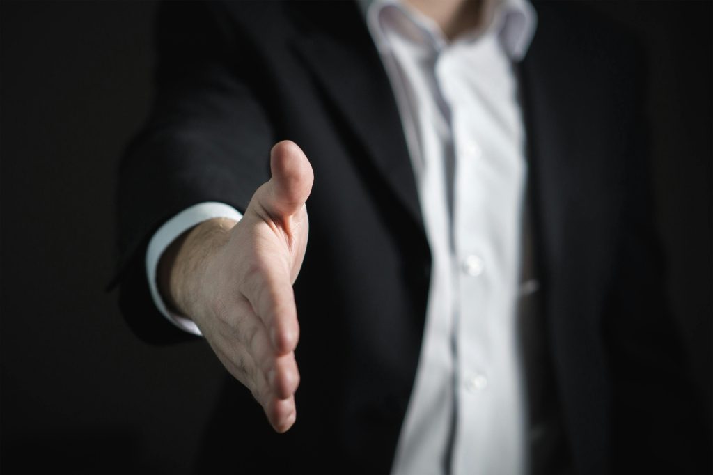 Man reaching out hand for a hand shake. How To Sell B2B